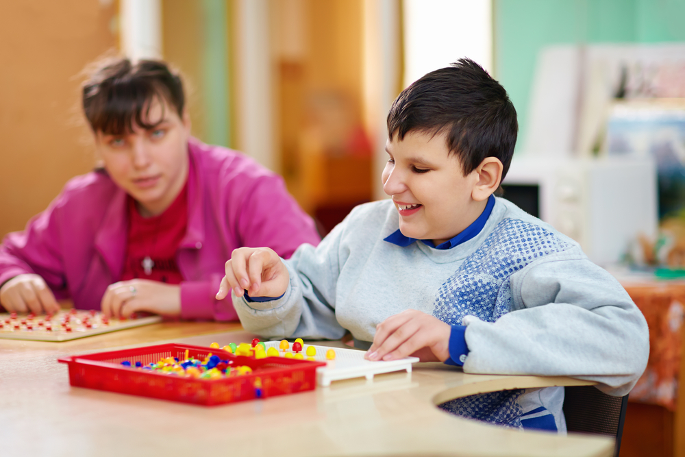 z prawej strony dziewczynka i chłopiec grają w gre edukacyjną, każde z nich cierpi na chorobę genetyczną