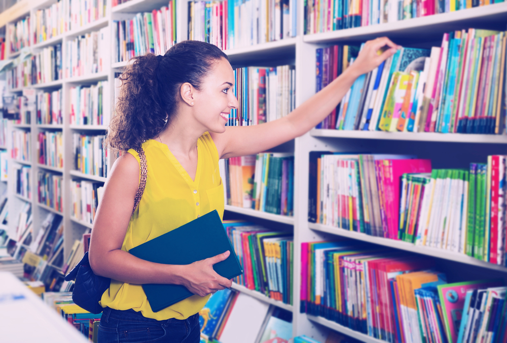 Studentka logopedii znajduje się w bibliotece, szuka książek, które pomogą jej w nauce